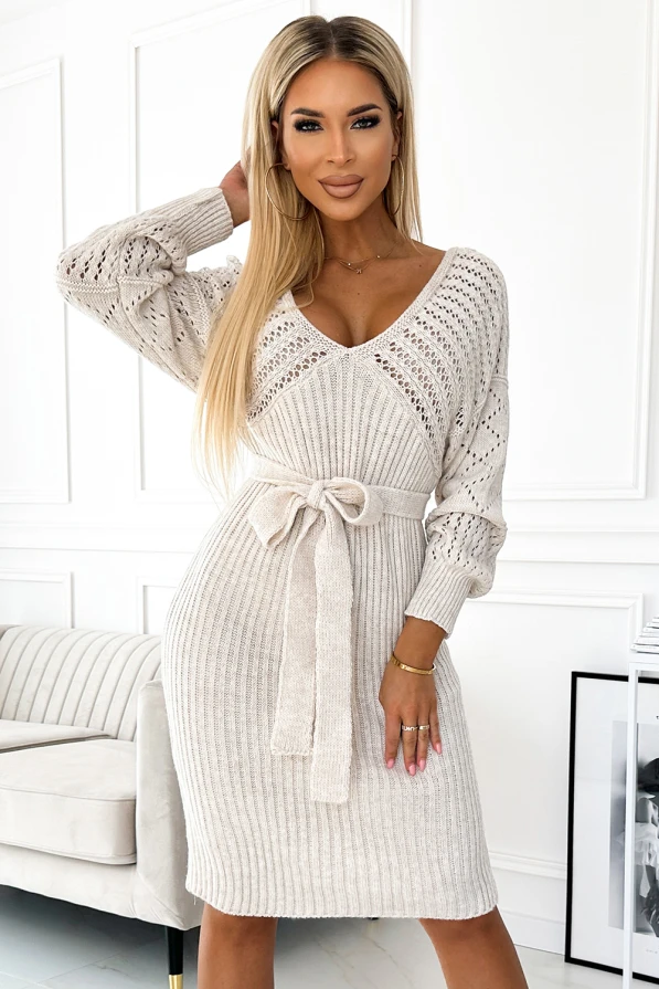 Rochia tricotată cu model ajurat are un design elegant și feminin, evidențiat de o curea în talie care subliniază silueta. Materialul moale și confortabil face această piesă ideală pentru zilele răcoroase.