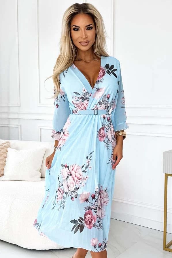 Rochia plisată Yuna este de culoare albastru deschis, decorată cu un imprimeu floral delicat în nuanțe de roz și verde. Are un design elegant cu mâneci lungi și un cordon în talie, perfectă pentru ocazii speciale.