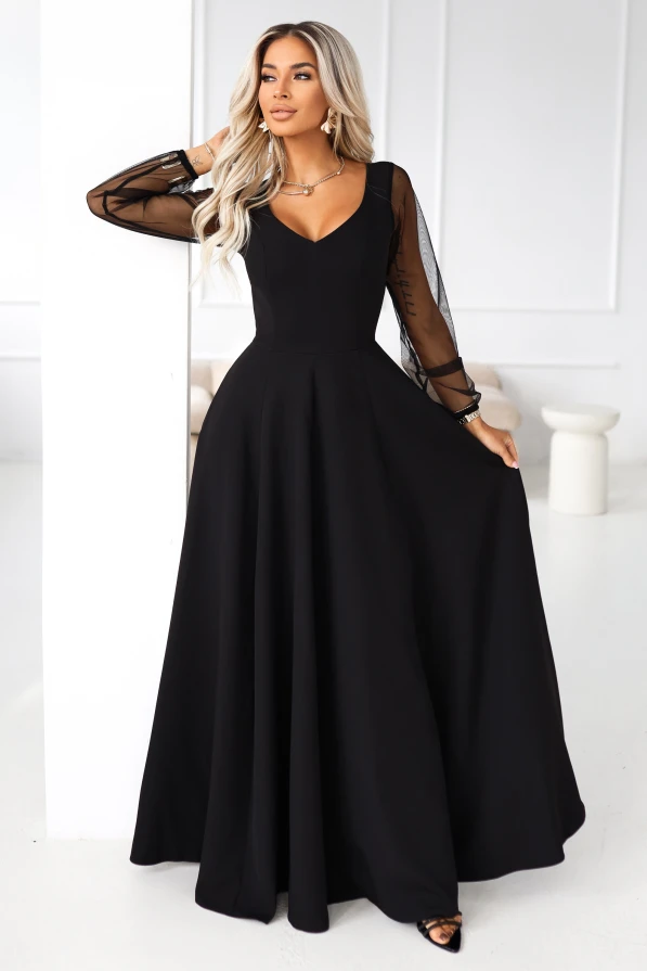 Modelka prezentuje elegancką czarną suknię maxi z tiulowymi rękawami i rozkloszowanym dołem.