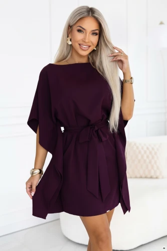 Model purtând o rochie kimono Numoco în culoarea prunei coapte, cu decolteu barcă, mâneci largi, curea legată la talie și laturi drapate, cu lungimea chiar deasupra genunchilor.}