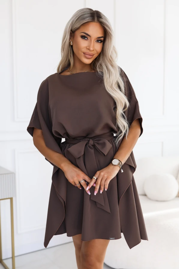 Model purtând rochia SOFIA de la Numoco în nuanța maro mocha. Rochia ajunge chiar deasupra genunchilor, are decolteu barcă, mâneci late de tip fluture și o curea legată la talie în fundă.